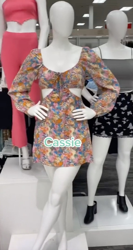 A floral cut-out dress is on display, with the mannequins hands placed on its hips. 
