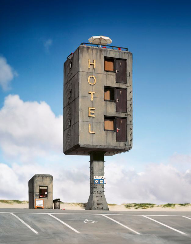 A miniature hotel stands in front of a blue sky. 
