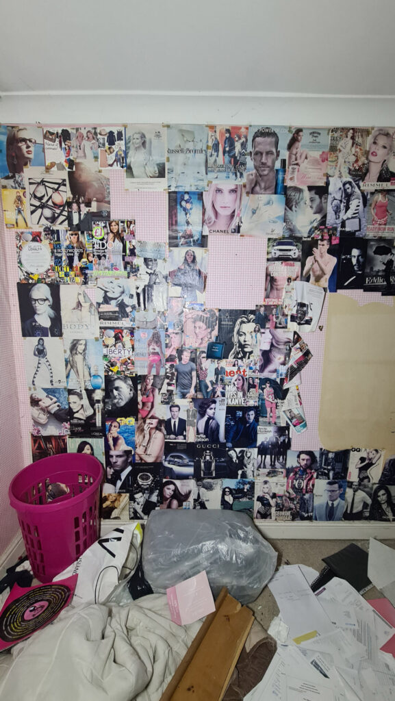 Magazine covers and multiple photos covers the pink wall as a pink bucket sits below