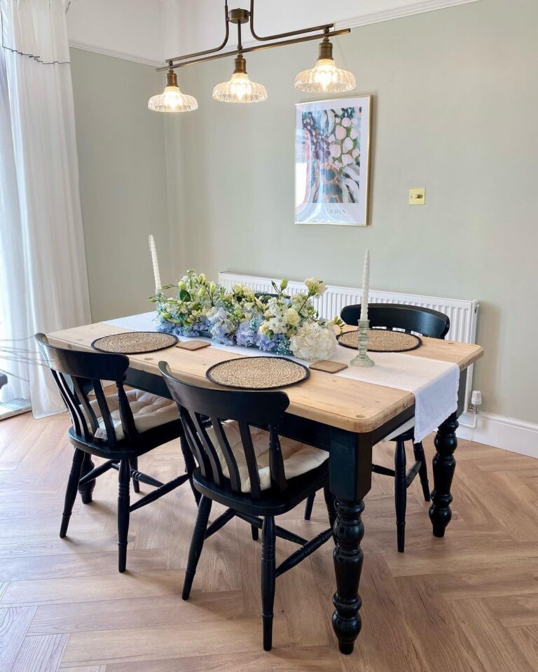 Olive green walls, laminate flooring and a bespoke dining table with black chairs