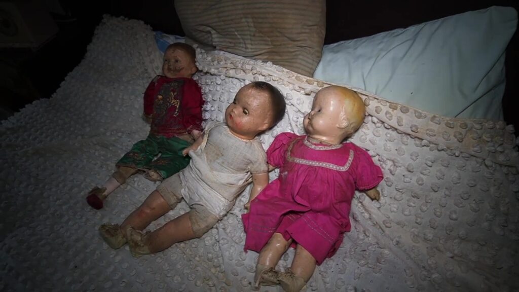 3 dolls line up on a bed in the abandoned property