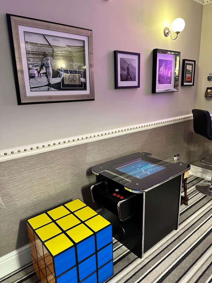 A rubiks cube chair, game table and photos of celebs line the wall in the games room. 